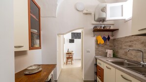 A narrow kitchen with a wooden table, a sink, and a dining area visible in the background. - 3482 Vico dei Mille by Barbarhouse (Tuglie)