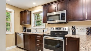 Una cocina moderna con armarios de madera oscura, electrodomésticos de acero inoxidable y encimera de granito.
