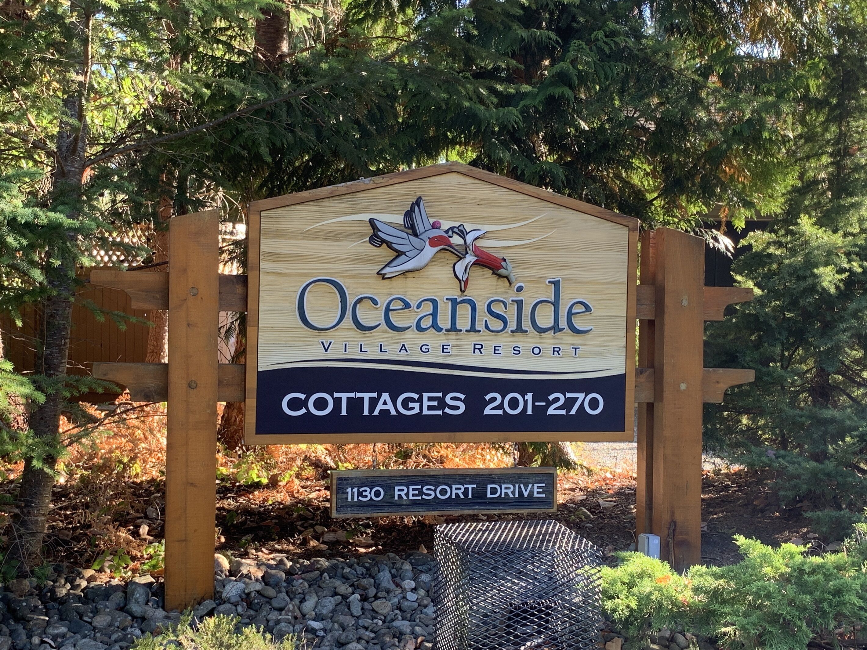 Schild für die Cottages des Oceanside Village Resort, mit Kontaktdaten und Adresse.