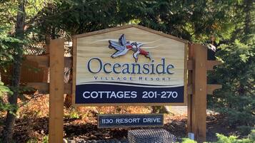 Schild für die Cottages des Oceanside Village Resort, mit Kontaktdaten und Adresse.