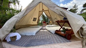 A tent with a bed inside, a welcome mat, and a wooden trolley with a bottle. - Khu nghi duong Kala Campark (Bao Thuan)