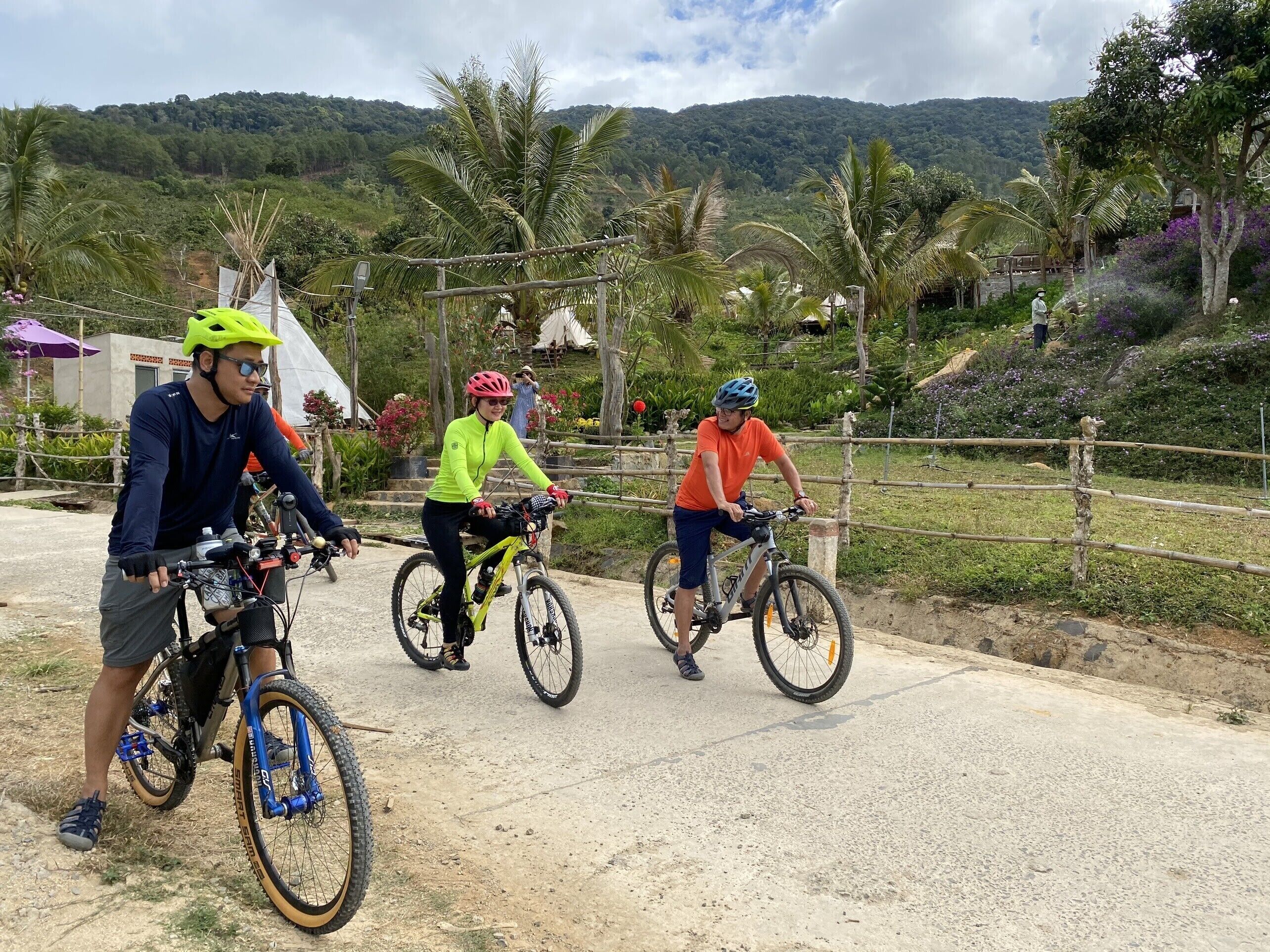 Tres ciclistas en un sendero de tierra con montañas al fondo.