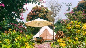 A tent with a canopy, surrounded by lush greenery and flowering plants. - Khu nghi duong Kala Campark (Bao Thuan)