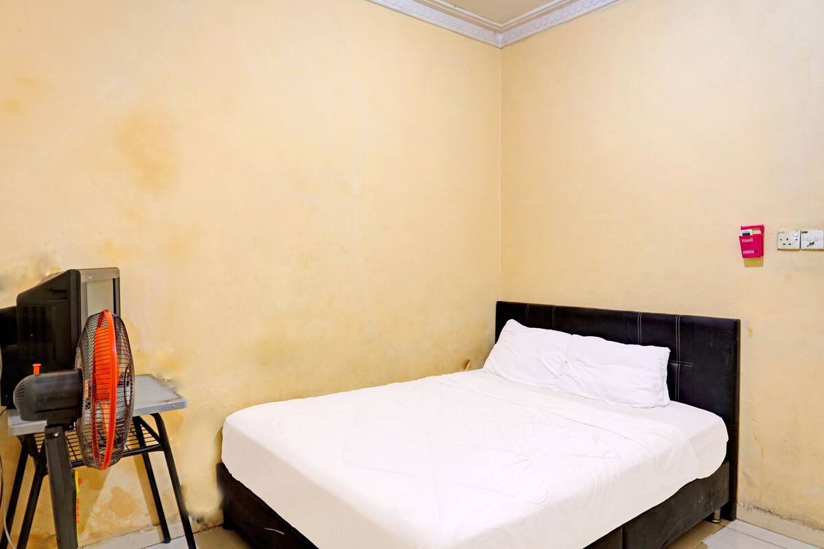 A room with a bed, a TV, and a fan.