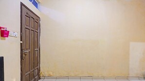 A room with a closed wooden door, a tiled floor, and a plain wall. - Hotel O Toyo Homestay Syariah (Batam)