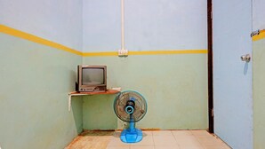 A small room with a blue fan, a television on a shelf, and a door. - Hotel O Toyo Homestay Syariah (Batam)