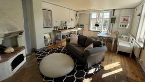 A cozy living room with a sofa, a coffee table, and a fireplace. There is a dining area with a table and chairs. The room has large windows and a view of the outside. - 2 Bed House Sleeps 4 With Garden & Free Parking (Ronneby)