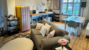 A cozy living room with a sofa, a dining area with a table and chairs, a kitchen area with appliances, and a window providing natural light. - 2 Bed House Sleeps 4 With Garden & Free Parking (Ronneby)