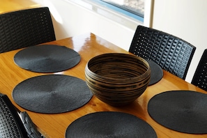 Six guests can dine comfortably around the table, surrounded by woven placemats and a large ceramic bowl.