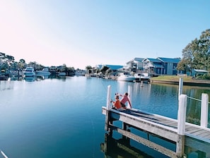 Guests can enjoy serene waterfront views from the dock, surrounded by boats and a residential building.