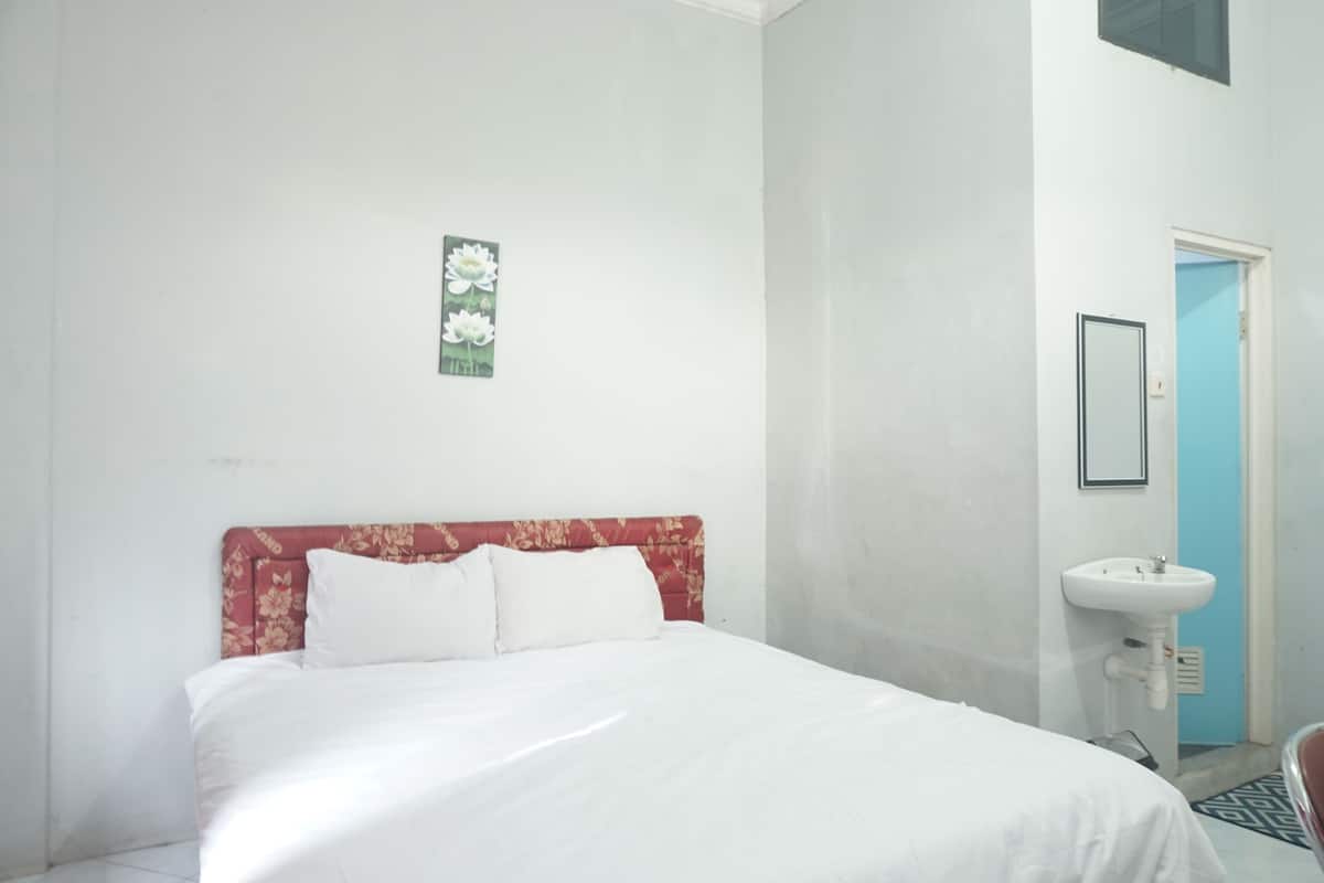 Une chambre à coucher avec un lit, un miroir fixé au mur et un lavabo.