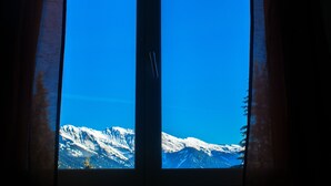 A window with a view of snow-covered mountains and a clear blue sky. - Malixerhof (Churwalden)
