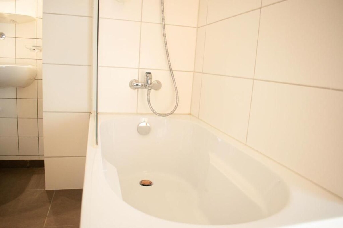 A bathroom with a white bathtub, a shower, and a sink.