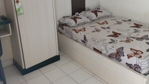 A single bed with a butterfly-themed bedspread, a wardrobe, and a small shelf unit. - SPOT ON 93005 Berkah Kedawung Syariah Near Fakultas Farmasi Universitas Muhammadiyah Ahmad Dahlan Cirebon (West Cirebon)