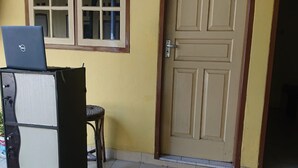 A room with a closed door, a chair, and a laptop on a stand. - SPOT ON 93005 Berkah Kedawung Syariah Near Fakultas Farmasi Universitas Muhammadiyah Ahmad Dahlan Cirebon (West Cirebon)