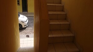 A staircase leading to a yellow door, a white car parked outside, and a pair of shoes on the ground. - SPOT ON 93005 Berkah Kedawung Syariah Near Fakultas Farmasi Universitas Muhammadiyah Ahmad Dahlan Cirebon (West Cirebon)
