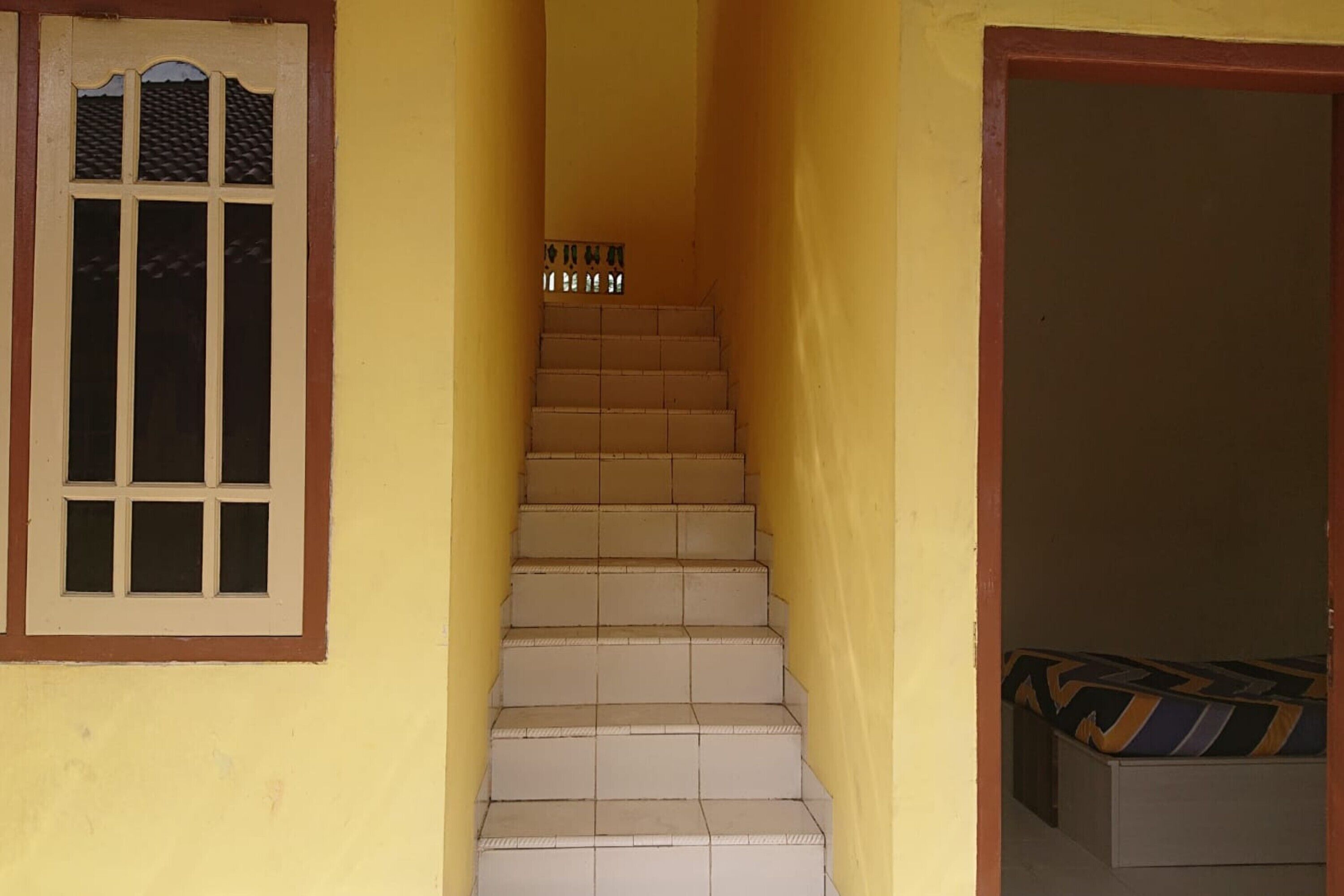 A narrow staircase with beige steps leading to a landing.