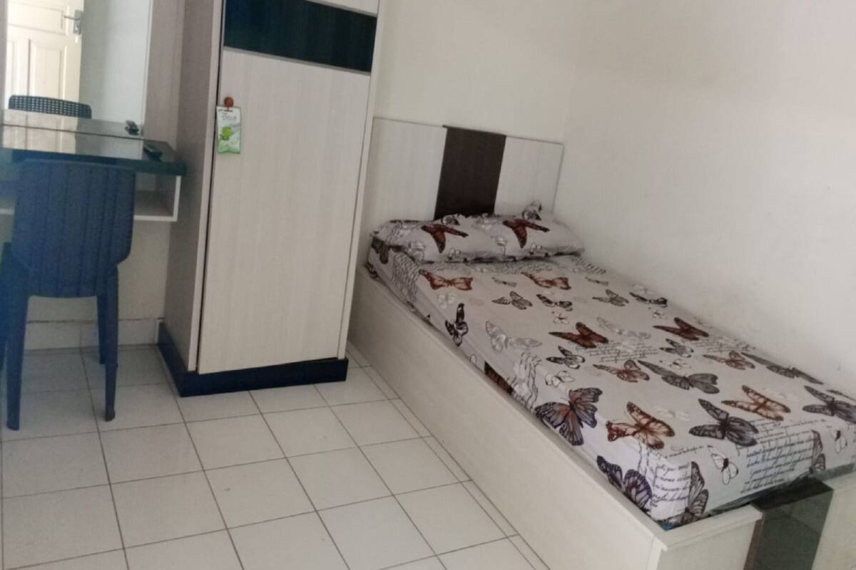 A small room with a bed, a desk, and a chair.