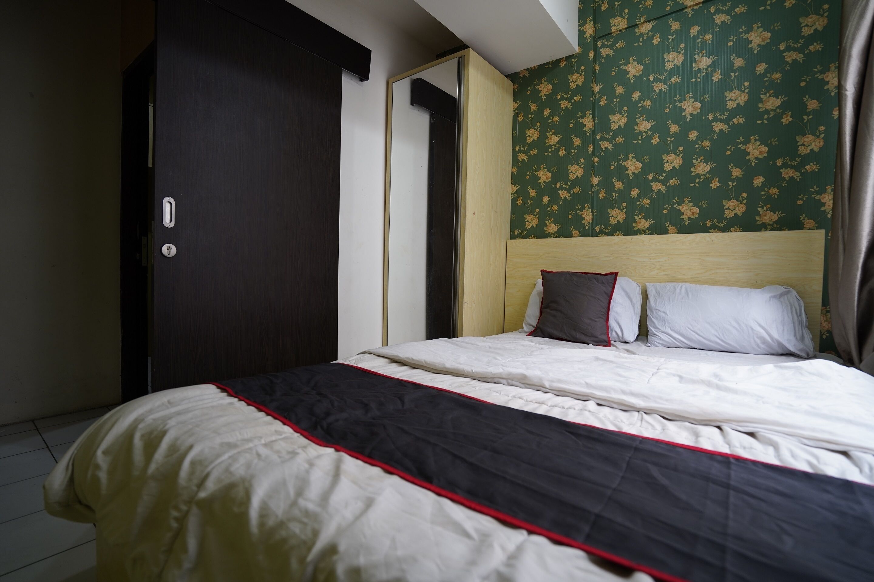 A bedroom with a bed, a wardrobe, and a floral wallpaper.