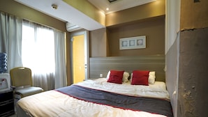 A hotel room with a large bed, a chair, a desk, and a window with curtains. - Collection O 92981 Apartemen The Jarrdin By Gold Suites PropertyNearSTEI ITB: Sekolah Teknik Elektro dan Informatika ITB (Bandung)