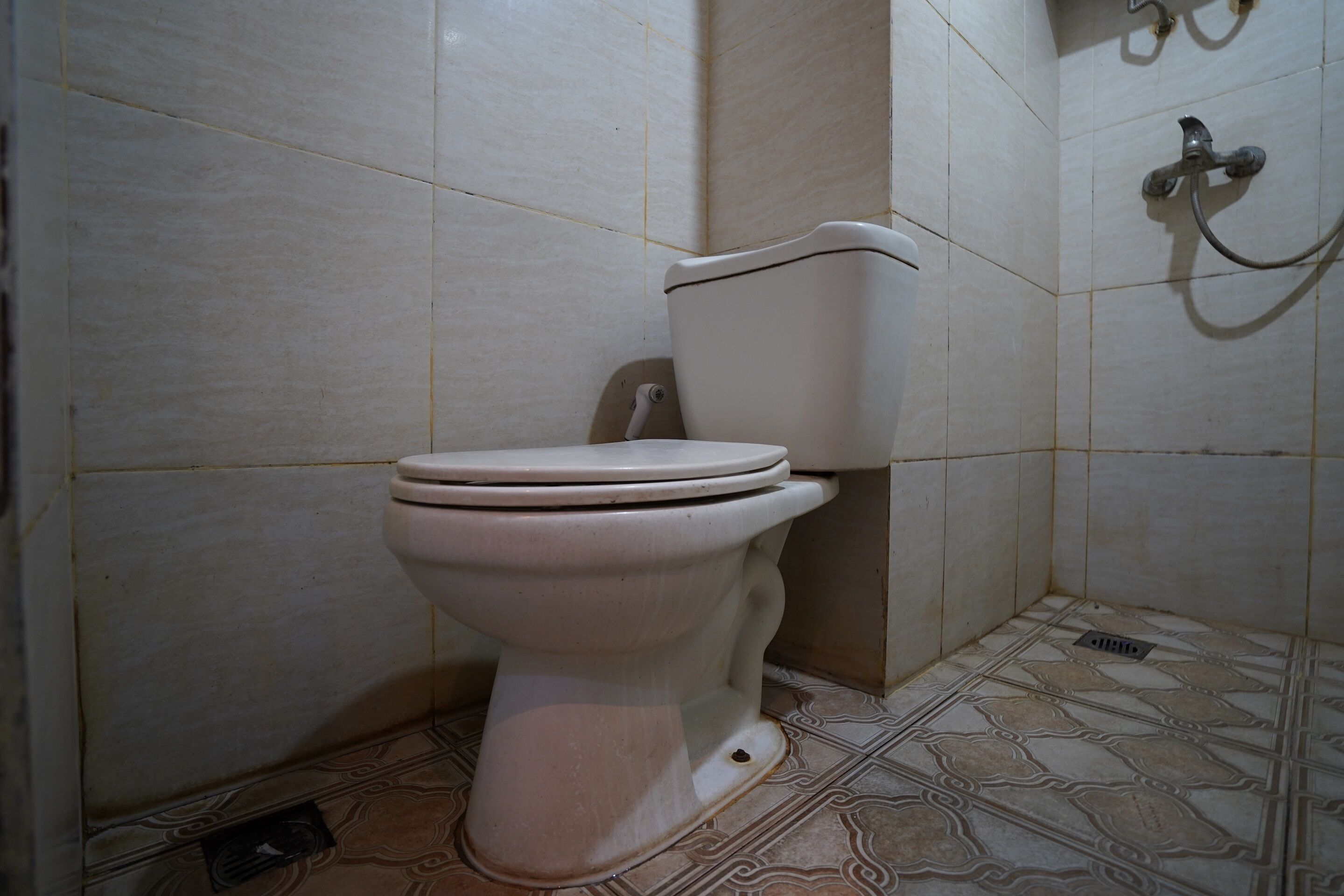 A toilet in a bathroom with tiled walls and floor.