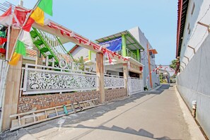A narrow street with a white decorative fence, a building with a green roof, and a clear blue sky. - Capital O 92929 Hotel New Tirta Kencana Syariah (Tegal)