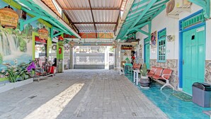 A covered outdoor area with a tiled floor, benches, and a bicycle. - Capital O 92929 Hotel New Tirta Kencana Syariah (Tegal)