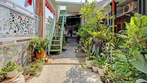 A narrow pathway flanked by potted plants and a green staircase leading to a building entrance. - Capital O 92929 Hotel New Tirta Kencana Syariah (Tegal)