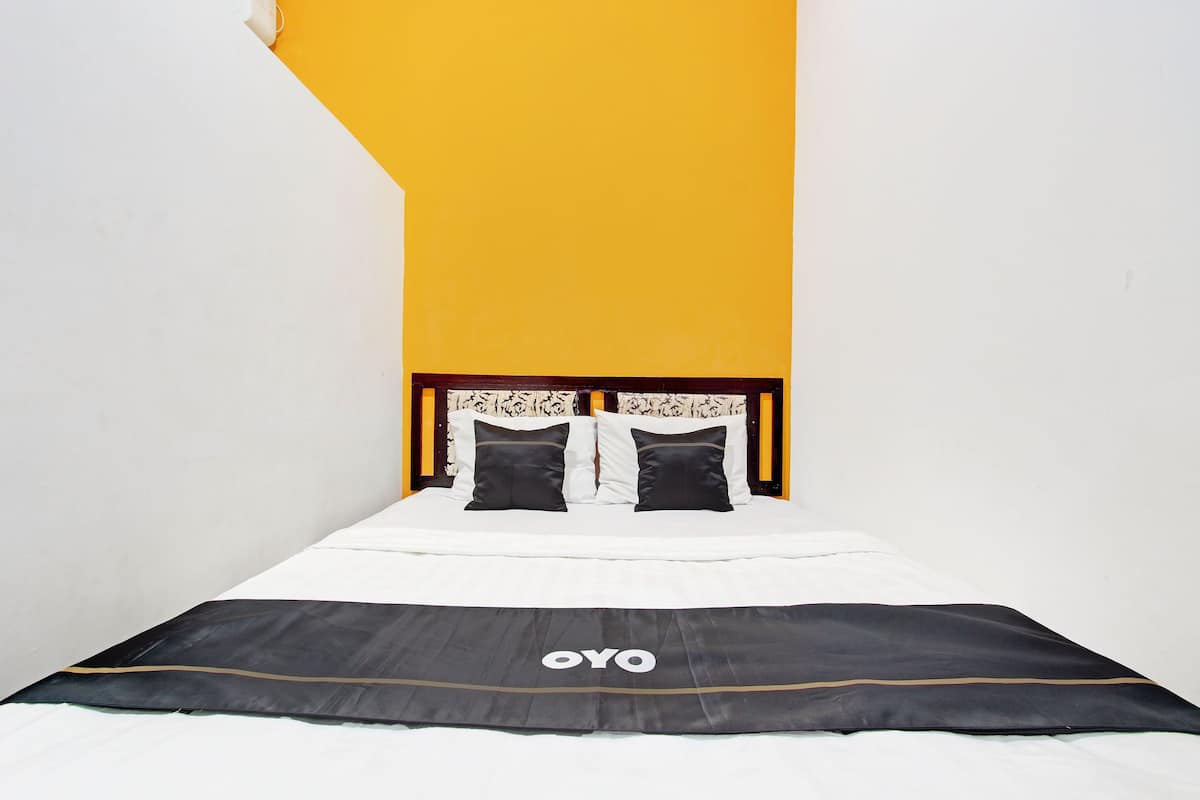 A bed with a white and black bedspread, a wooden headboard, and a yellow wall.