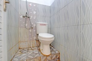 A small bathroom with a toilet, shower, and patterned tiles. - Capital O 92929 Hotel New Tirta Kencana Syariah (Tegal)