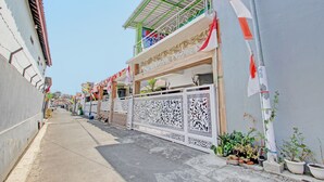 A narrow street with buildings on either side, decorative fences, and potted plants. - Capital O 92929 Hotel New Tirta Kencana Syariah (Tegal)
