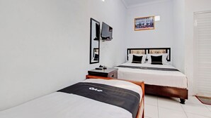 A hotel room with two beds, a TV, a small table, and a calendar on the wall. - Capital O 92929 Hotel New Tirta Kencana Syariah (Tegal)