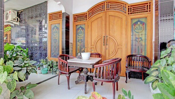 A room with a wooden cabinet, a table with chairs, and various potted plants. - Capital O 92929 Hotel New Tirta Kencana Syariah (Tegal)