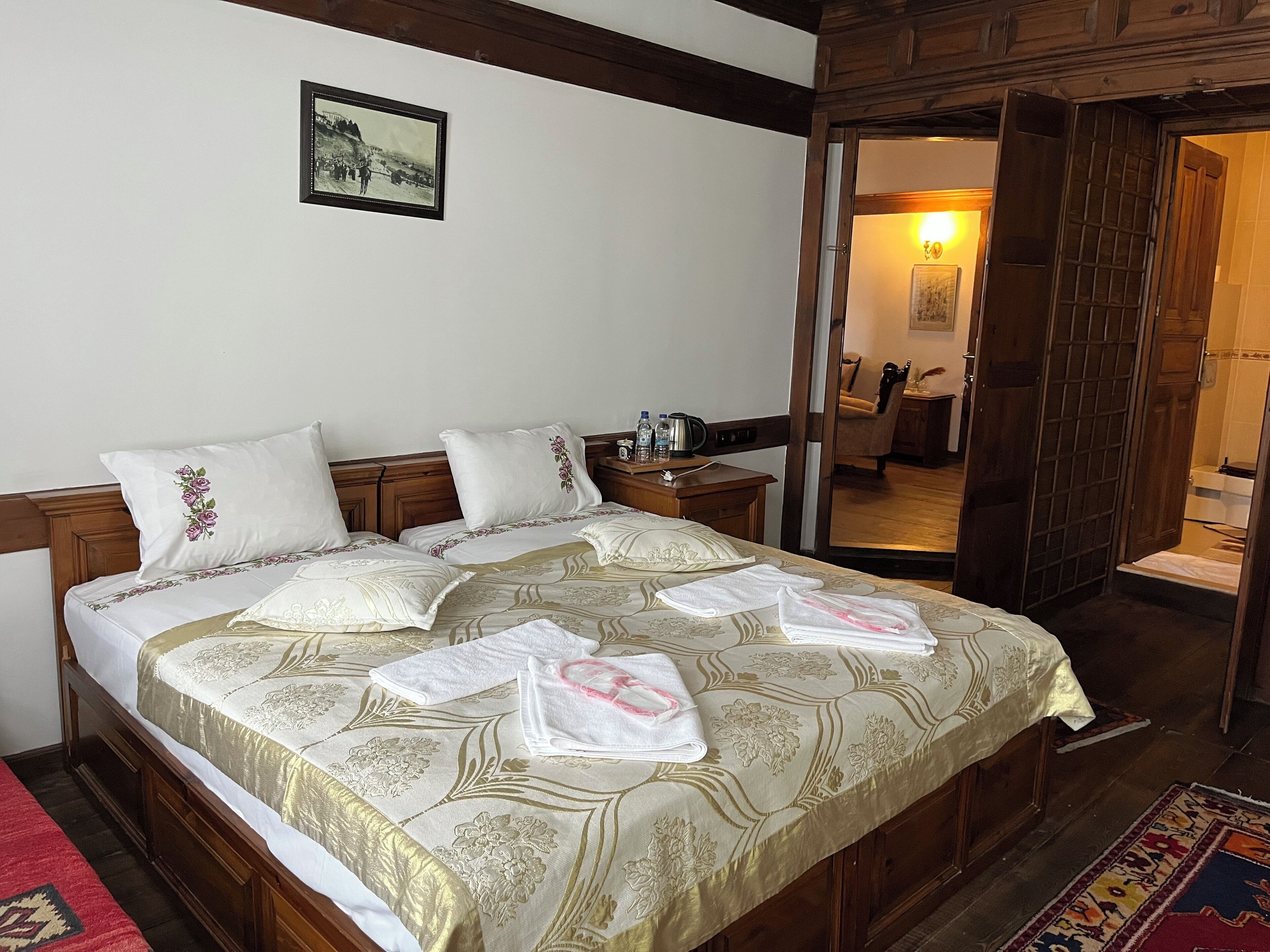 A neatly made bed with floral bedding, a bedside table with a lamp, and a framed picture on the wall.
