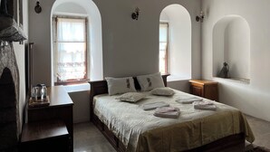 Una camera da letto con un letto, due finestre ad arco, un comodino e una lampada.