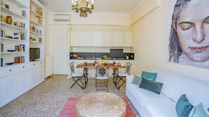 A modern living room with a white sofa, a dining table with chairs, and a large painting on the wall. - Lovely 1-bed Apartment in Venezia (Venice)