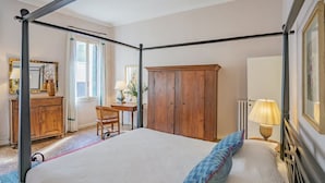 A four-poster bed with a wooden headboard, a wooden wardrobe, a desk with a chair, and a radiator. - Lovely 1-bed Apartment in Venezia (Venice)