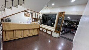 A modern kitchen with a wooden counter, a refrigerator, and a window overlooking a street. - Hotel Rajdhani (Latur)