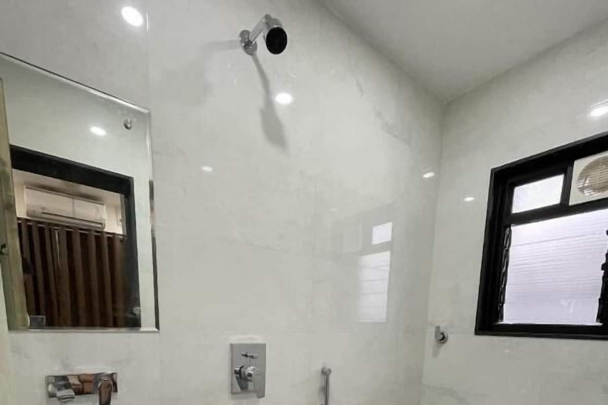 Une salle de bain équipée d’un lavabo, de toilettes, d’une douche et d’une poubelle bleue.