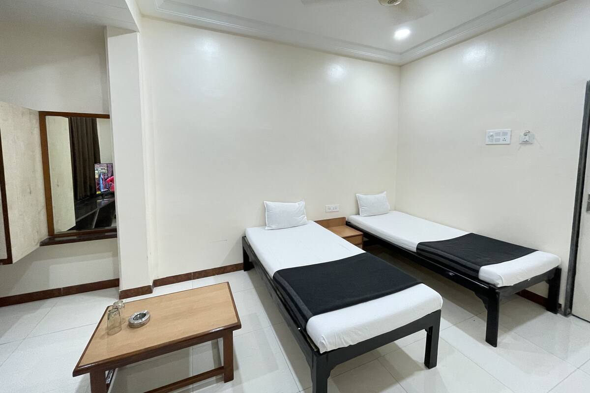 Une chambre avec deux lits simples, une petite table en bois et un ventilateur de plafond.