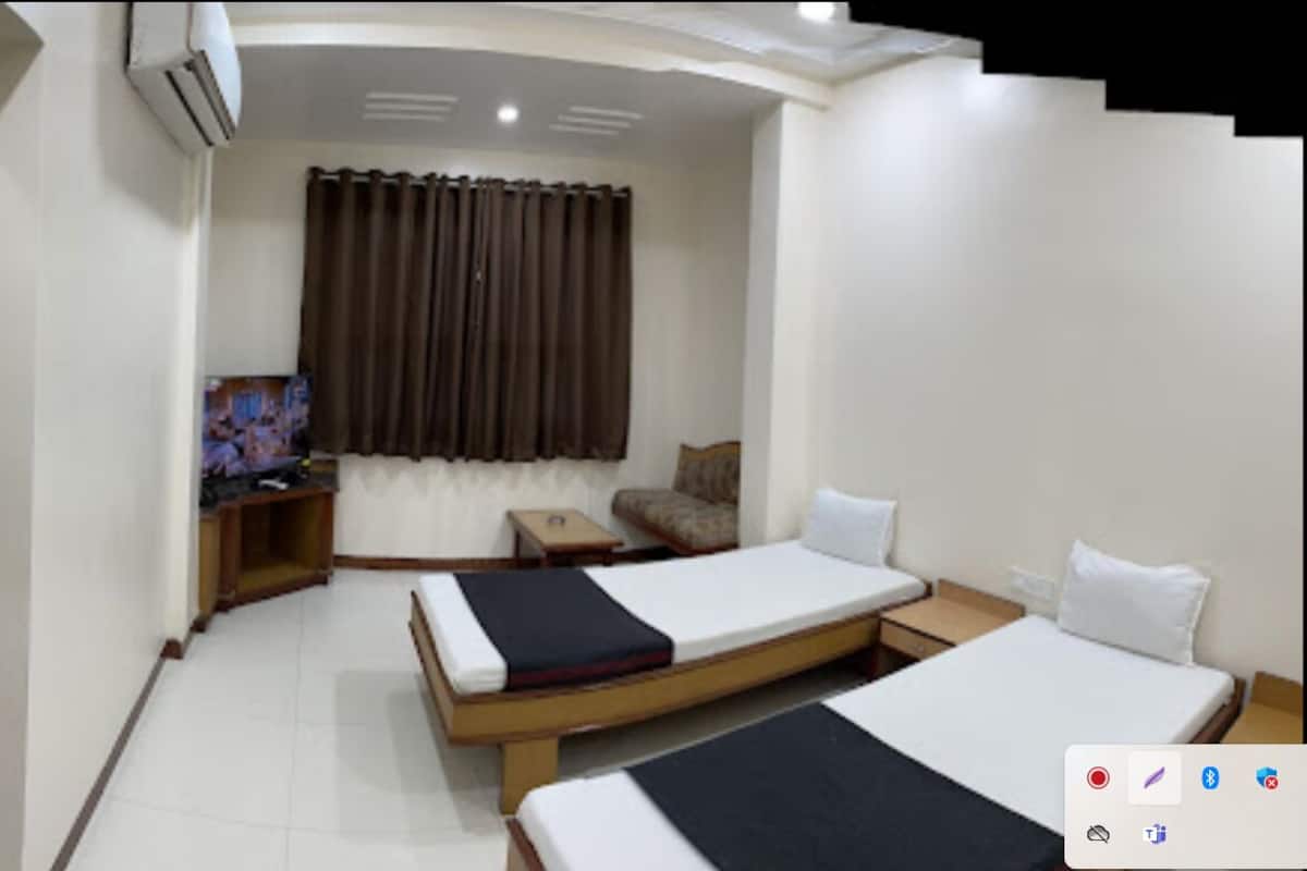 Une chambre d’hôtel avec deux lits, une télévision, une petite table et un rideau.