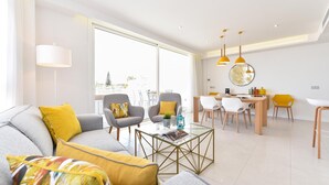 A modern living room with a sofa, armchairs, a coffee table, and a dining area with chairs and a table. - Mogan Beachfront V&L by VillaGranCanaria (Mogan)