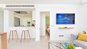 A modern living room with a sofa, a coffee table, and a kitchen area with bar stools. - Mogan Beachfront V&L by VillaGranCanaria (Mogan)