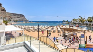 A beach resort with a large sandy area, a rocky cliff, and a clear blue sky. - Mogan Beachfront V&L by VillaGranCanaria (Mogan)