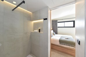 Une chambre d’hôtel moderne avec un grand lit, une table de chevet et une étagère intégrée agrémentée d’un vase.