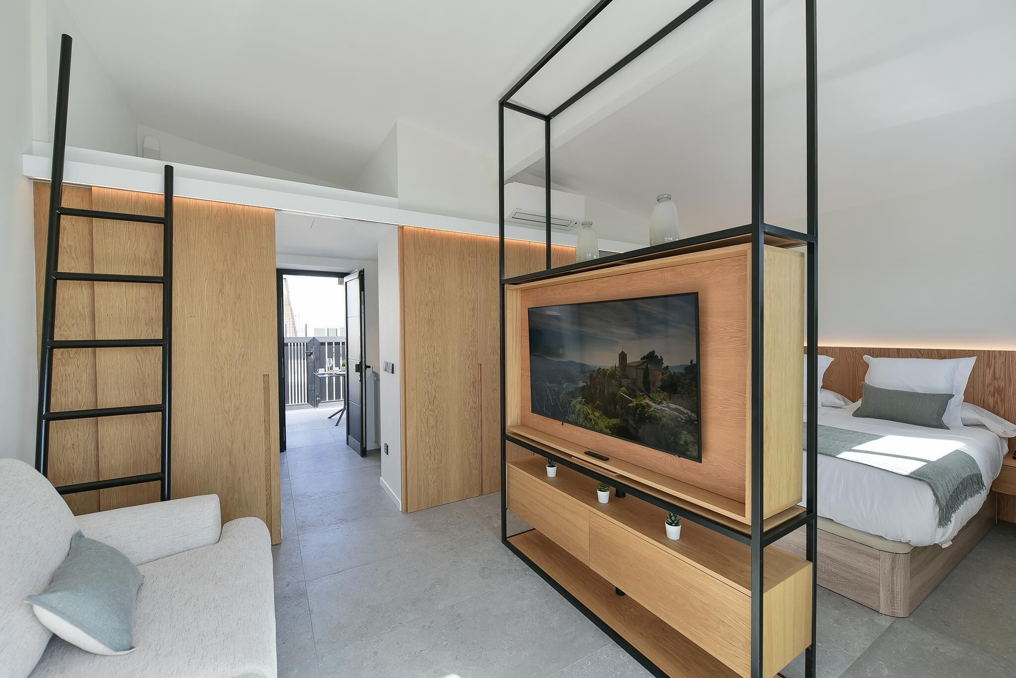 Une chambre d’hôtel moderne équipée d’une télévision, d’un canapé, d’un lit et d’une armoire en bois.