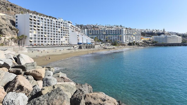 Um hotel à beira-mar com vários edifícios, uma praia de areia e um litoral rochoso.