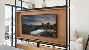Quarto moderno com uma cama grande, televisão montada e vista para o exterior.