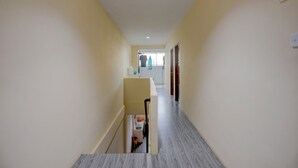 A narrow hallway with a tiled floor leading to a room with a window. - Hotel O Inara Homestay (Batam)