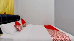 A hotel room with a bed, a headboard, and a curtain. - Hotel O Inara Homestay (Batam)